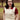 Dark-haired woman wearing cream cable knit tank top layered over red collar blouse