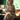 Blonde woman sitting on sofa in colorful retro brushstroke print shirtwaist dress