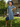 Woman in blue ditsy floral retro tea dress wearing wide brim hat, white gloves, and holding handbag