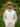 A man wearing a straw boater hat with a red and black band, a light blue dress shirt, and a beige cotton linen vest and matching pants, standing in a lush green garden with yellow flowers.