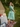 Woman in retro green floral short sleeve day dress looking back over shoulder outdoors