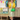 Blonde woman posing by vintage caravan wearing yellow Daydream cardigan and green bag