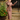 Woman in 1940s brown wool feel suit with diamond inset details checking compact mirror