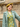 Model in a sage green coat and floral dress wearing the yellow pure wool classic beret