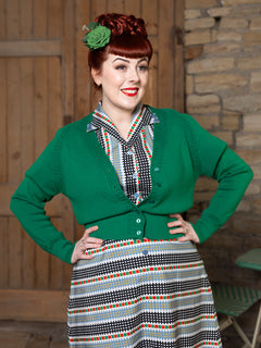 Woman wearing green Daydream cardigan over Dreamboat Carousel dress, front view