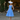 Woman posing in 1950s sky blue polka dot swing dress wearing white hat, lace gloves, and heels